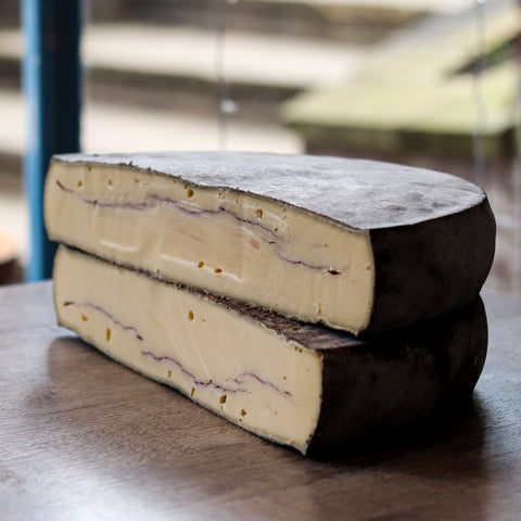 ive rare artisan cheeses displayed on wooden board with tasting notes