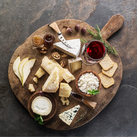 European cheese tasting box with 7 artisan cheeses, crackers and quince jelly on wooden board